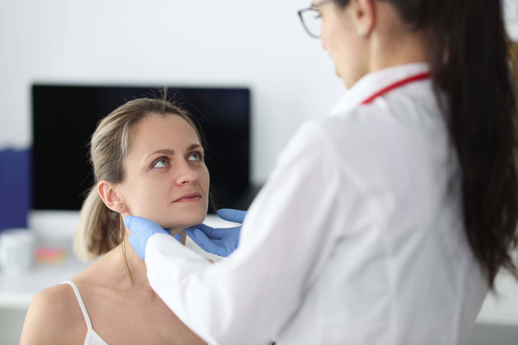 Ärztin tastet bei einer Patientin die Lymphknoten am Hals ab.